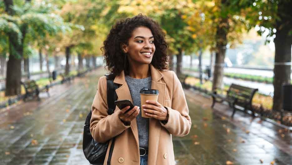 Beautiful young african woman wearing coat walking outdoors