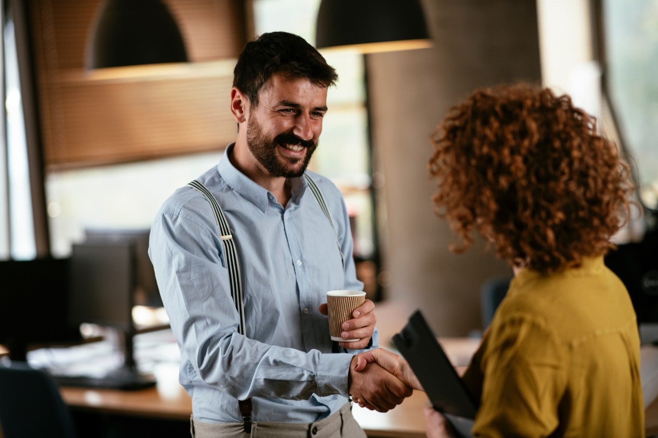Colleagues in office. Businesswoman and businessman handshake in office..	