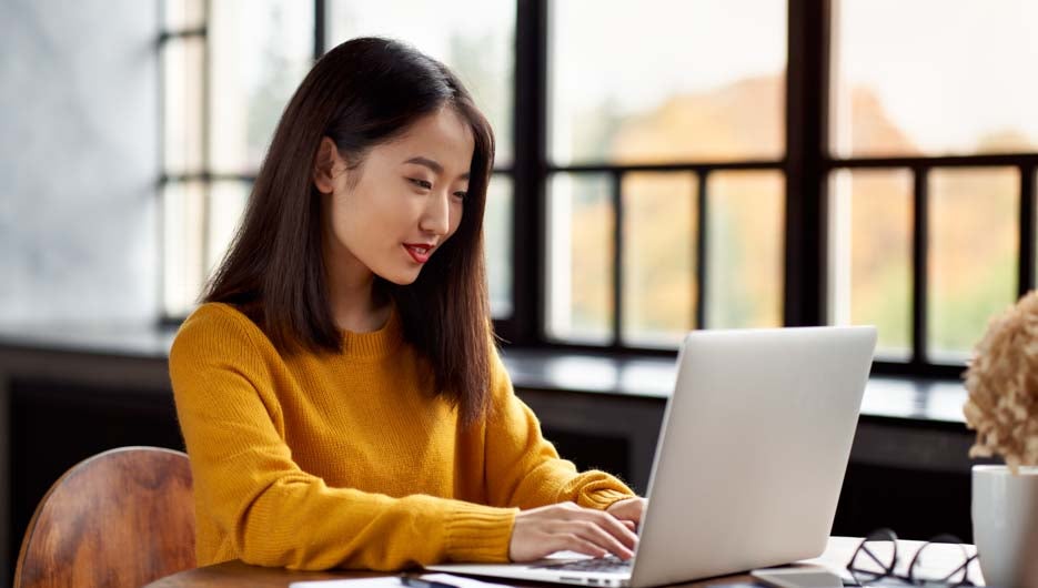 Asian woman working on laptop at home or in cafe. Young lady in 