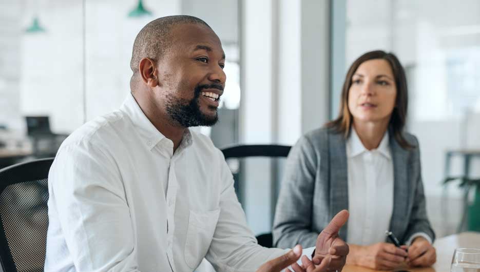 Smiling African American businessman talking with coworkers duri