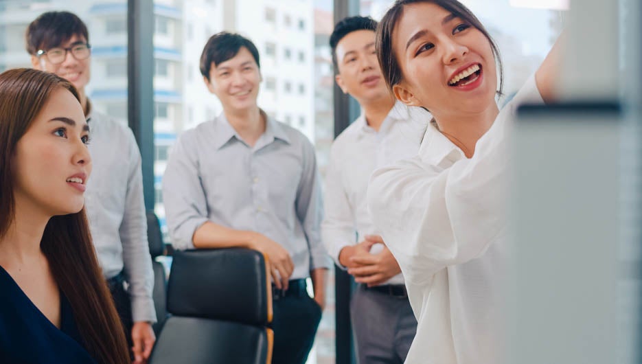 Asia businessmen and businesswomen meeting brainstorming ideas conducting business presentation project colleagues working together plan success strategy enjoy teamwork in small modern office.
